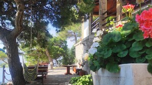 A stone pathway leading to outdoor seating with a hammock and a table. - Josip Blue Horizon Apartments (Ston)