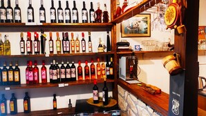 Une cave à vin avec des étagères remplies de bouteilles, un comptoir en bois et un mur en pierre.