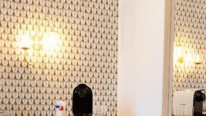 A compact room with a small black side table, a sofa, and a wall-mounted light fixture. - Risorgimento 55 (Rome)