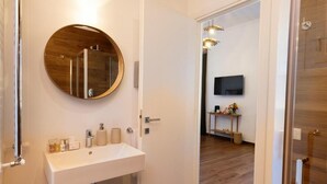 A bathroom with a round mirror, white sink, and wooden flooring. - Risorgimento 55 (Rome)