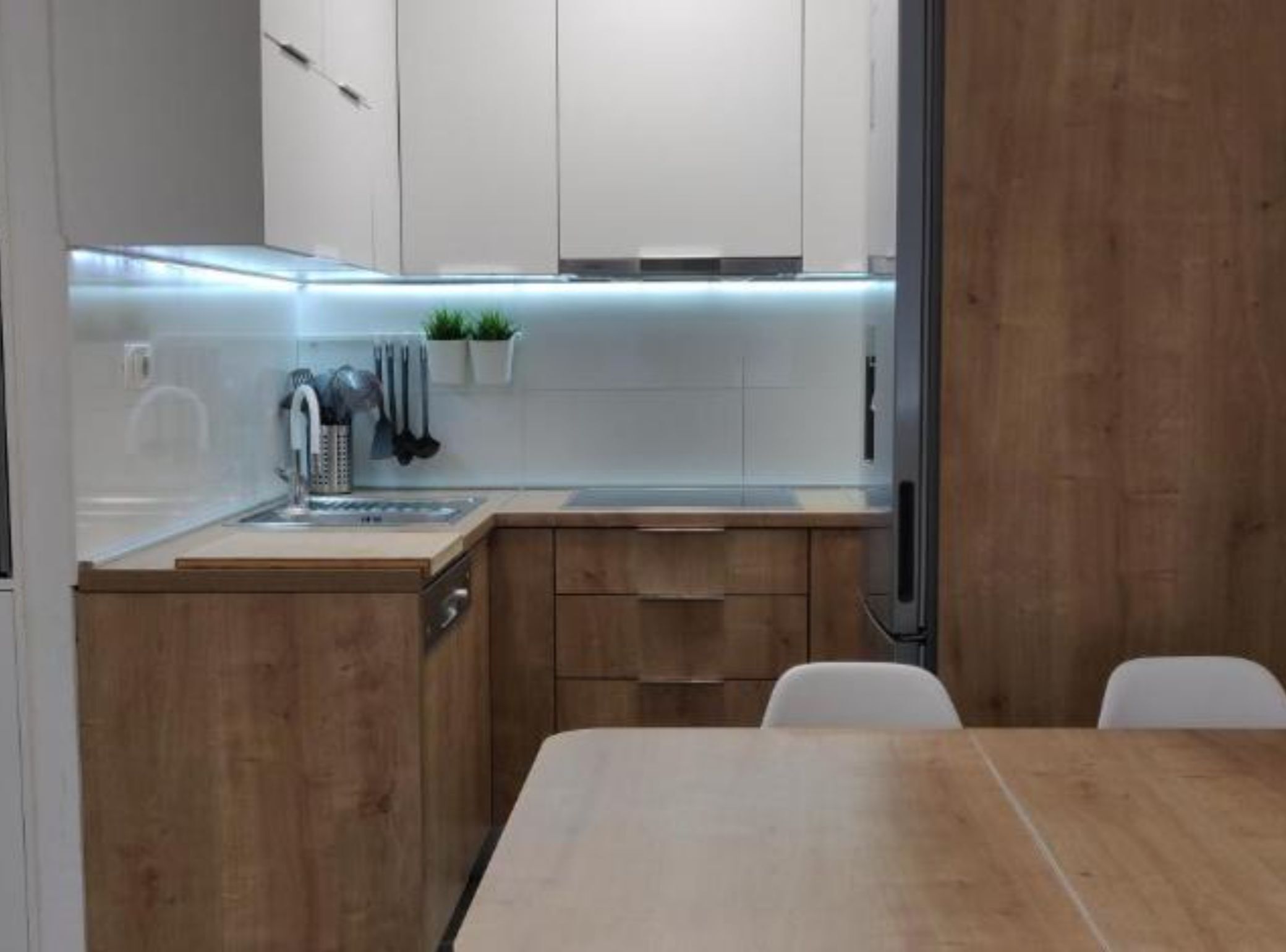 A modern kitchen with wooden cabinets, a stainless steel sink, and a dining area with a wooden table.