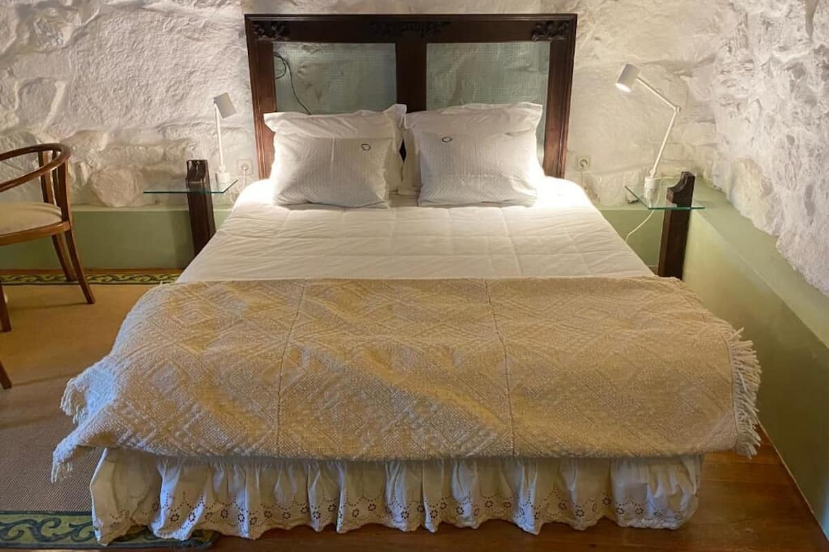 A bed with a wooden headboard, two bedside lamps, and a bedside table with a lamp.