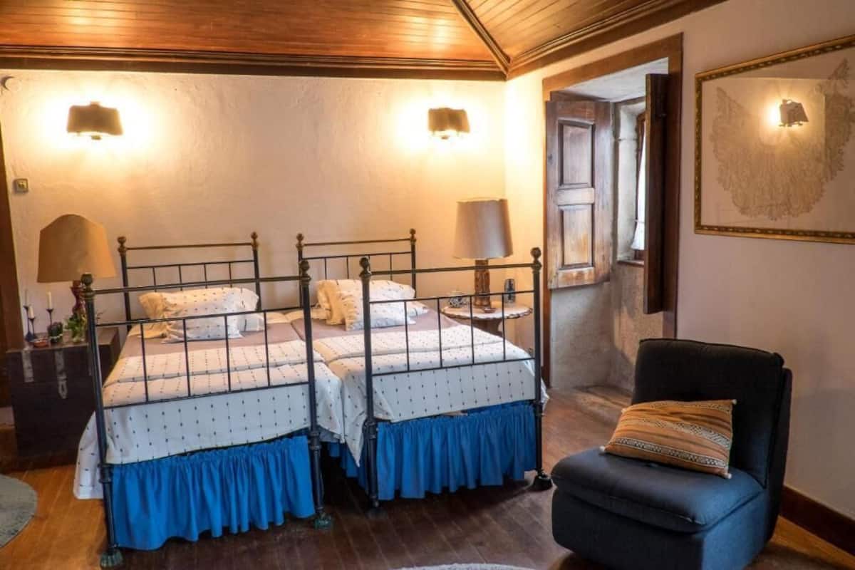 A room with two beds, a chair, and a lamp.