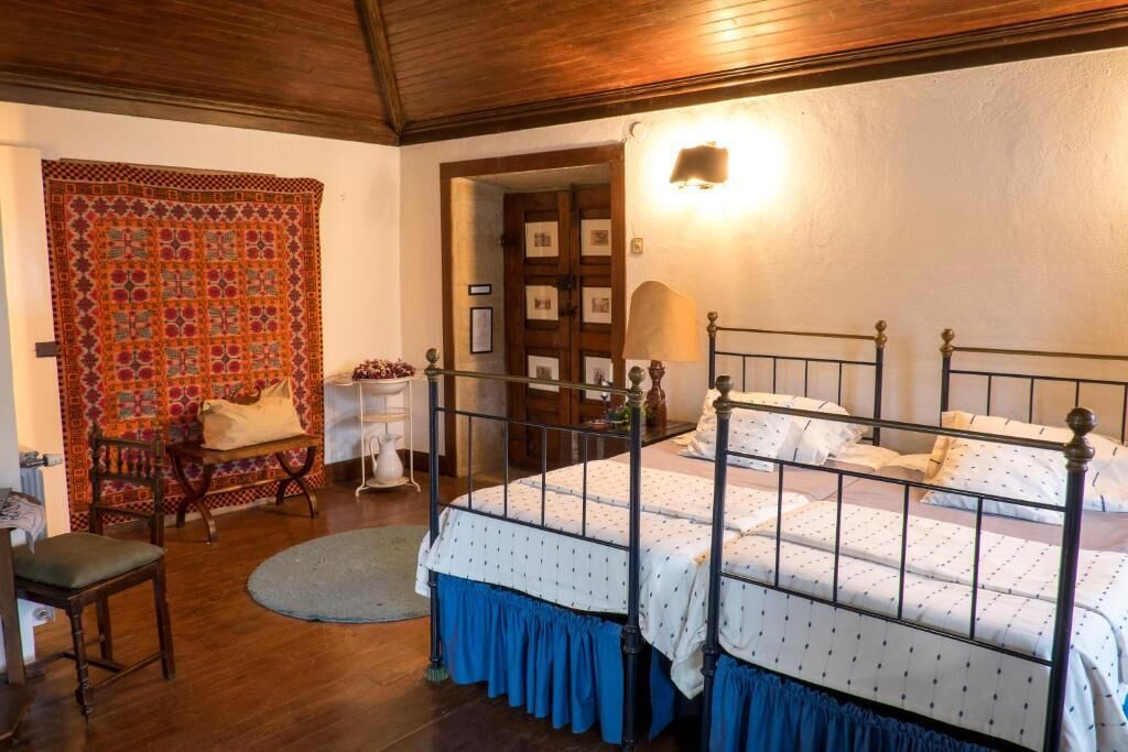 Un dormitorio con cama con dosel, una silla, una mesa y un tapiz decorado.