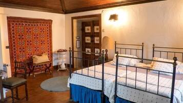 Un dormitorio con cama con dosel, una silla, una mesa y un tapiz decorado.