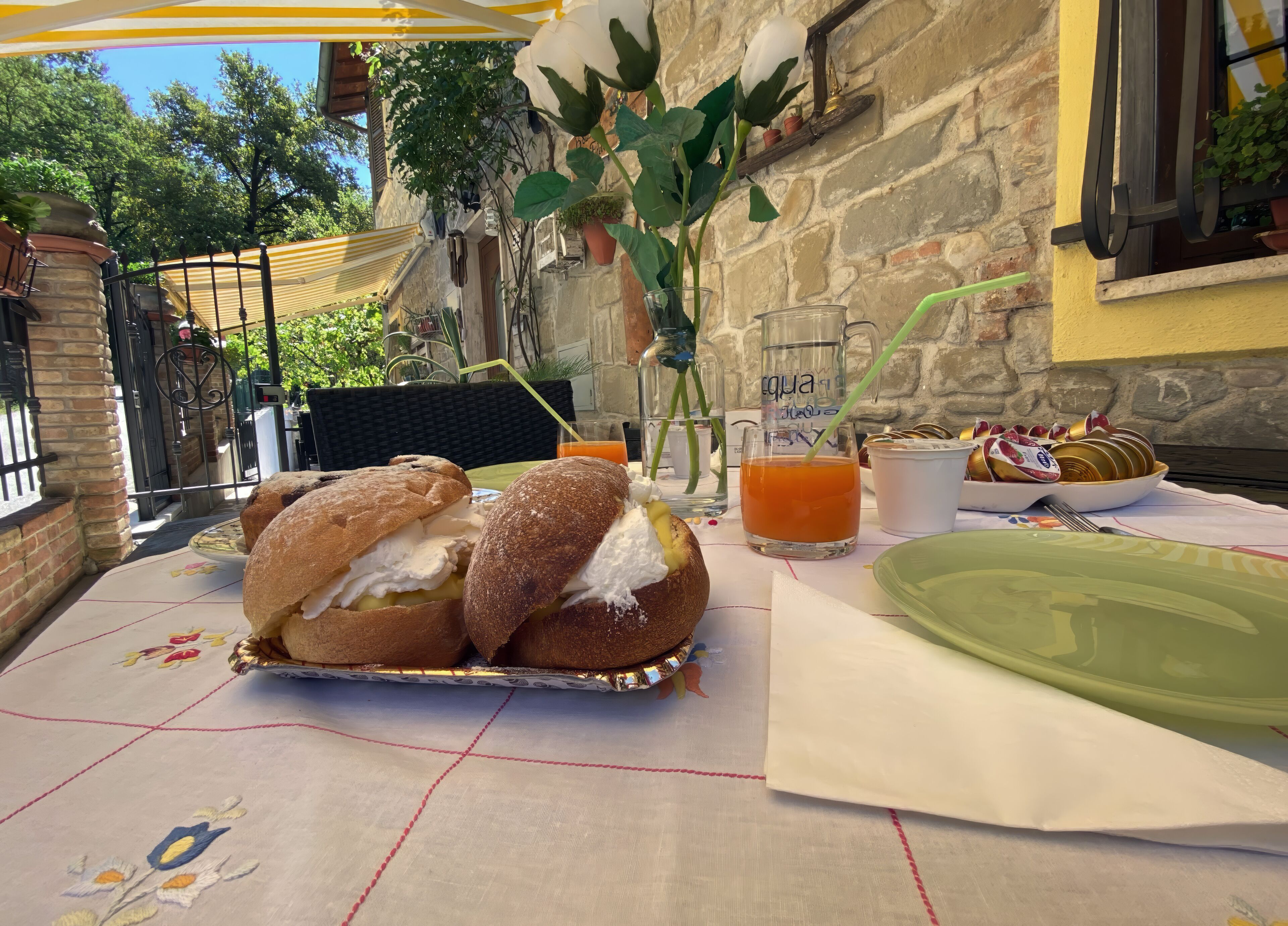 Un espace de restauration en plein air avec une table dressée pour deux personnes, comprenant des sandwichs, une boisson et une assiette de pâtisseries.