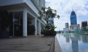 A modern building with a pool, large windows, and a view of a tall skyscraper. - Quill Residences KLCC Luxury Suite by Maju Inn King Suite with Balcony (Kuala Lumpur)