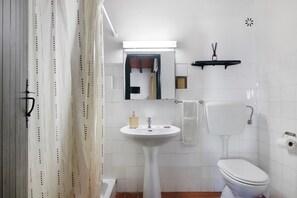 Een badkamer met een witte wastafel, toilet en douchegordijn.