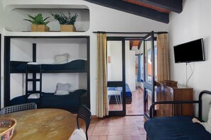 Une chambre avec des lits superposés, une télévision, une table et une chaise.