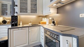 Une cuisine moderne avec des meubles blancs, un four encastré et un plan de travail en granit.