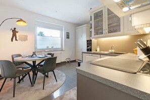 A modern kitchen with a dining area, featuring a round table, chairs, and a pendant light. - Revierruhe Apartment – Modern Comfort in Marl with Garden Views (Marl)