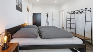 Une chambre à coucher moderne avec un lit, une lampe de chevet, un porte-manteau et une armoire.