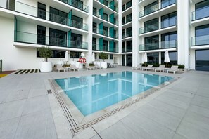 Un edificio moderno con piscina, varios balcones y zonas de estar al aire libre.