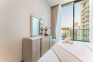 Una habitación de hotel moderna con una cama grande, un aparador, un espejo y vistas de un edificio alto.