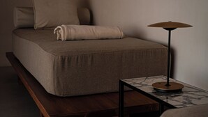 Ett minimalistiskt sovrum med en säng, ett sängbord och en lampa.
