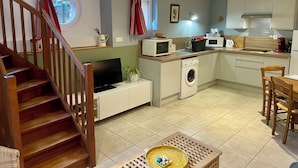 Une cuisine moderne équipée d’un lave-linge, d’un four à micro-ondes et d’un coin repas avec une table et des chaises en bois.