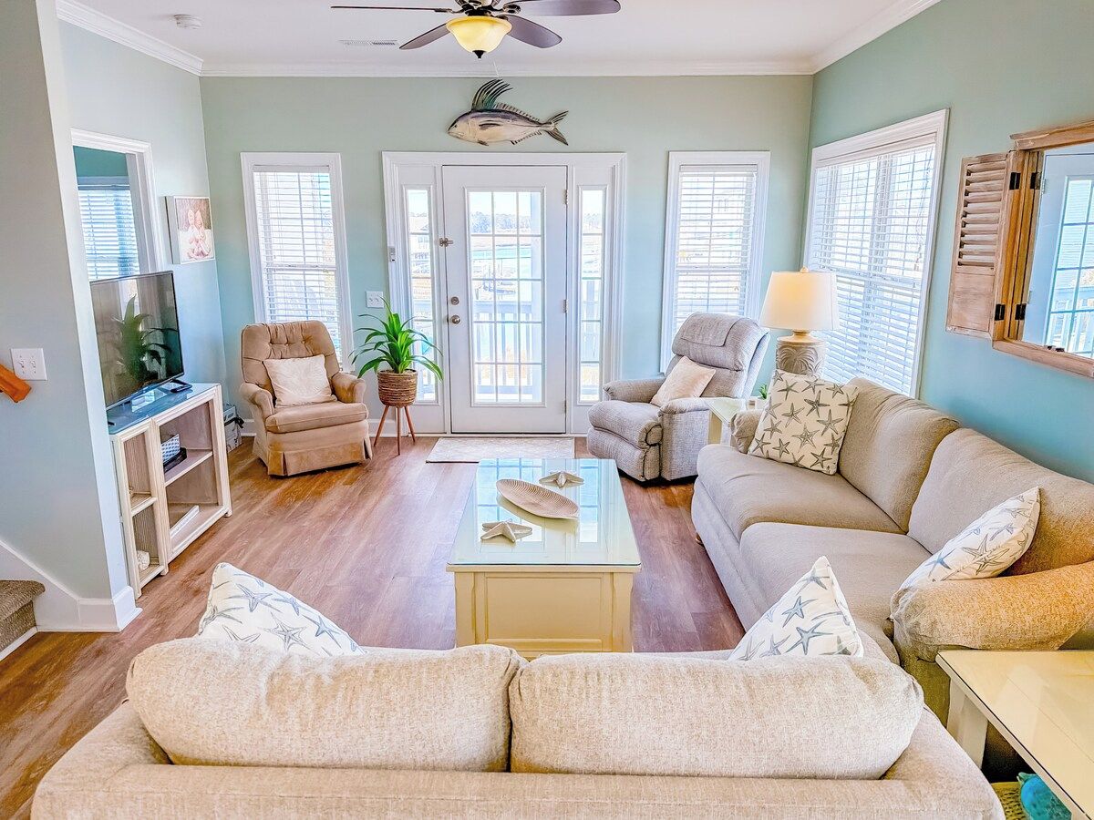 A living room with a sofa, armchairs, a coffee table, and a television.