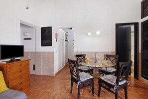 Um espaço habitável compacto com área de refeições, cozinha compacta e televisão sobre um aparador.