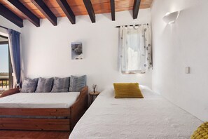 Une chambre avec deux lits, des têtes de lit en bois, une petite table de chevet, un tableau au mur et une fenêtre avec des rideaux.