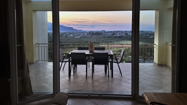 Ein Balkon mit Tisch und Stühlen, Blick auf eine Berglandschaft und einen klaren Himmel.