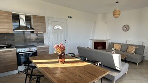 Eine moderne Küche mit Herd, Backofen und einer Essecke mit Holztisch und Stühlen.