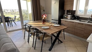 Eine moderne Küche mit Esstisch, Stühlen, einem Kühlschrank und Blick ins Freie.