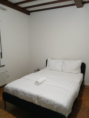 A single bed with white linens, a black headboard, and a wooden floor. - Nice to meet you. (Asse)