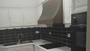 Eine Küche mit weißen Schränken, einer schwarzen Küchenrückwand mit Fliesen und einem schwarzen Ofen.