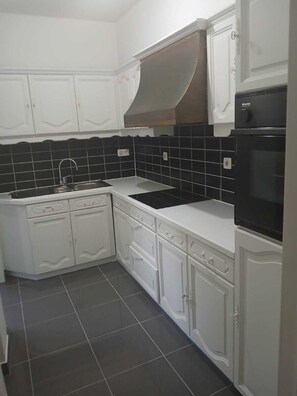A kitchen with white cabinets, black tiled backsplash, and a black oven. - Nice to meet you. (Asse)