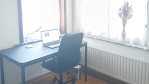 Ein Zimmer mit Schreibtisch, Stuhl, Laptop und Heizkörper.