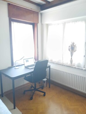 A room with a desk, chair, laptop, and a radiator. - Nice to meet you. (Asse)