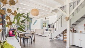 Une pièce spacieuse comprenant un coin repas, un escalier et donnant sur l’extérieur.