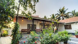 A courtyard with a covered seating area, potted plants, and a tiled floor. - ELIVAAS Breeze & Grains 3BHK with Patio (Kuttanad Taluk)