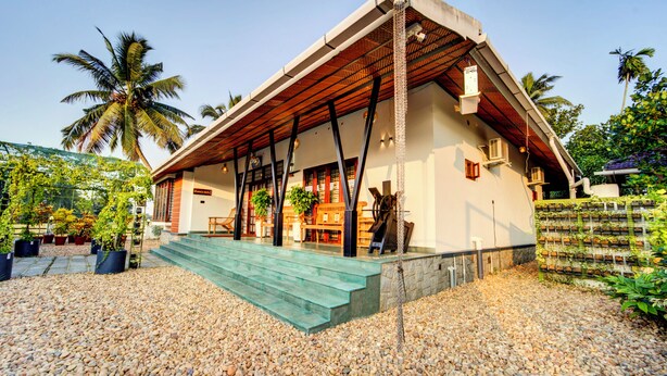 A house with a porch, steps, and a garden with palm trees. - ELIVAAS Breeze & Grains 3BHK with Patio (Kuttanad Taluk)