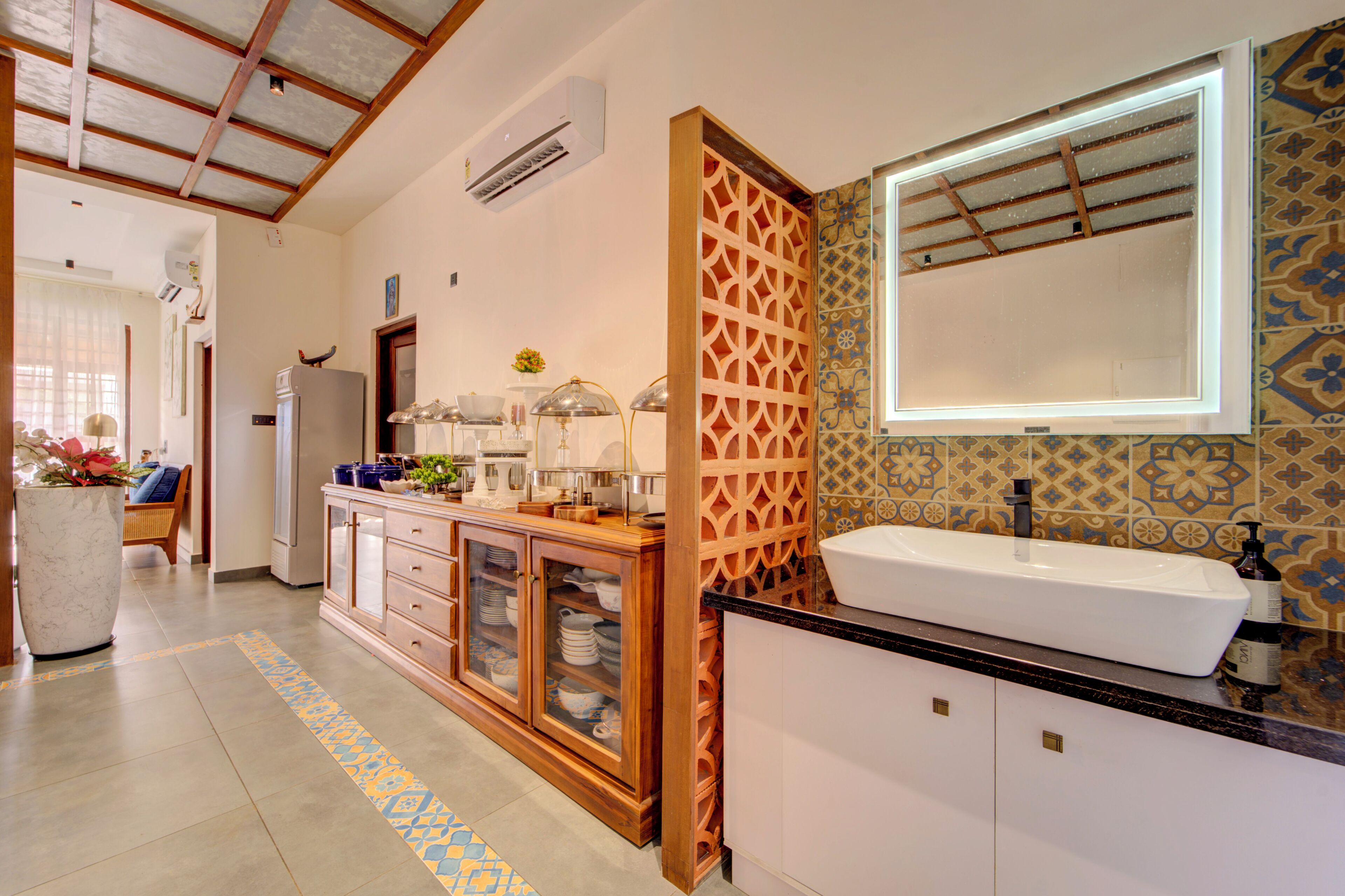 A modern bathroom with a large sink, mirror, and decorative tiles.