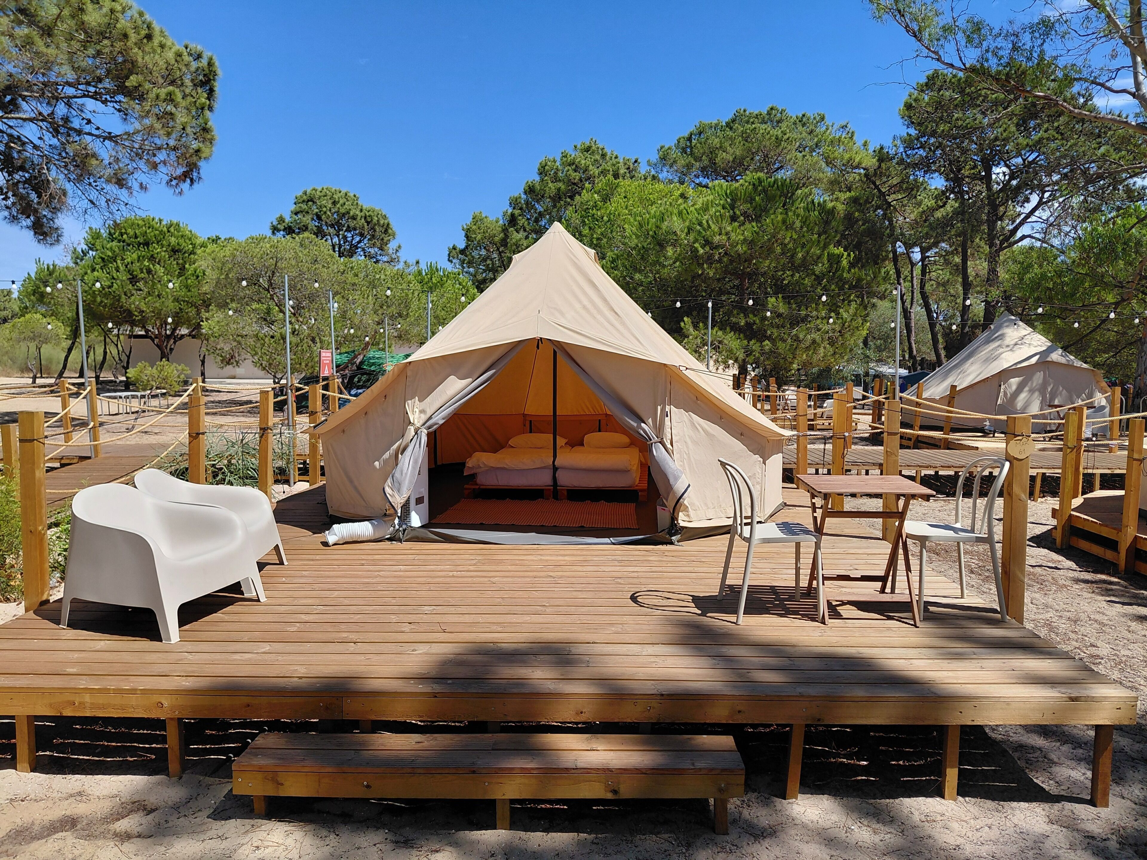 A tented accommodation with a wooden deck, a bed, and a seating area.