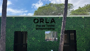 A building facade with a green wall and the text 'ORLA Ilha de Tavira Ecogamping'. - Orla Ilha de Tavira Eco-Glamping (Tavira)
