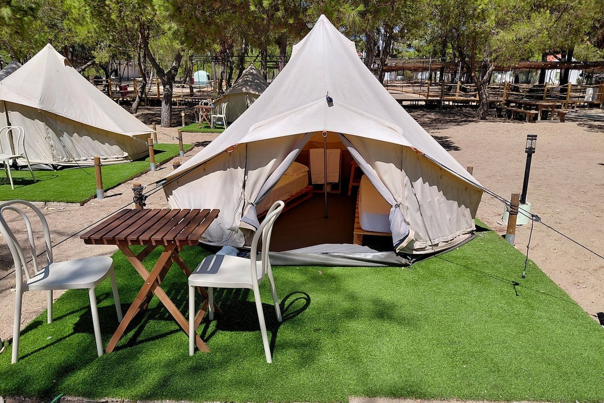 Ein Campingplatz mit Zelten, einem Tisch, Stühlen und Kunstrasen.
