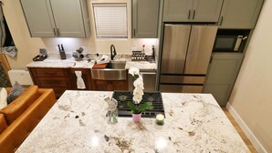 A kitchen with a marble countertop, stainless steel appliances, and a dining area with leather chairs.