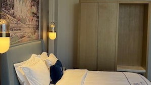 Habitación de hotel con cama, armario e iluminación en la pared.