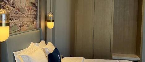 A hotel room with a bed, a wardrobe, and wall-mounted lights.
