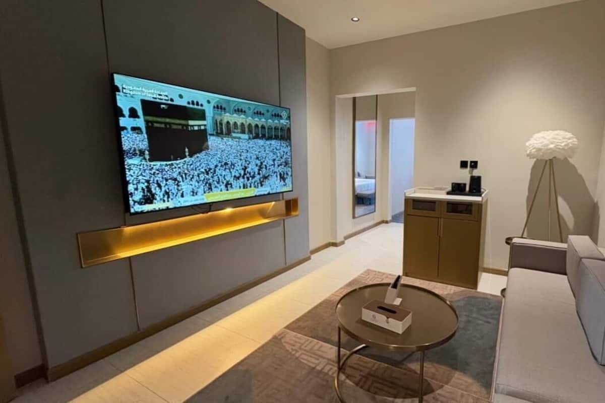 Une chambre d’hôtel moderne équipée d’un téléviseur à écran plat fixé au mur, d’un canapé, d’une petite table basse et d’un lampadaire.
