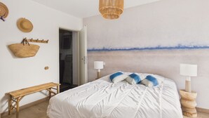 Ein Schlafzimmer mit Bett, einer Bank, einer hängenden Pflanzkorb und einem Bild an der Wand.