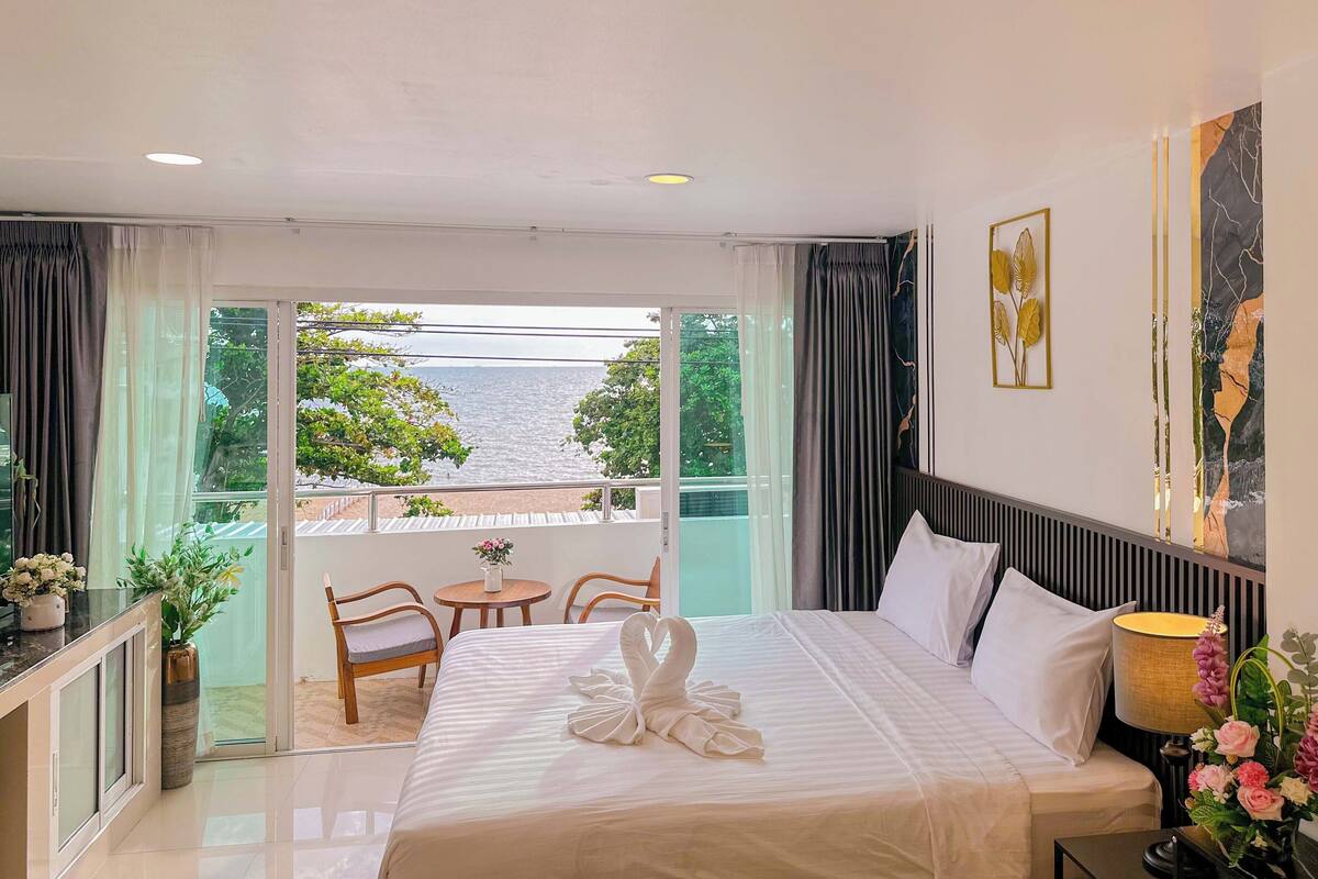 Habitación de hotel con cama, una mesita, una silla, una mesita de noche y vista al mar.