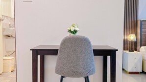 Une chaise avec un coussin gris et un petit arrangement floral blanc, placée devant une table en bois foncé.