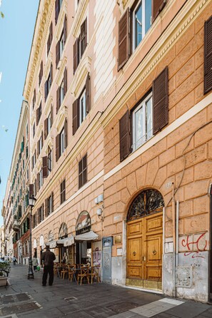 Un edificio con una puerta de madera grande, varias ventanas y mesas al aire libre.