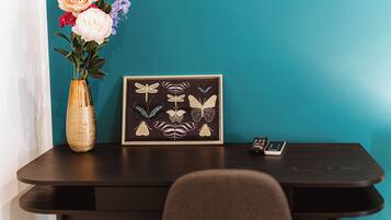 A dark wooden table with a framed botanical illustration, a vase with flowers, and a remote control.