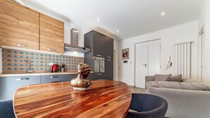 Une cuisine moderne avec des meubles en bois, un four encastré et un coin repas comprenant une table ronde et des chaises.
