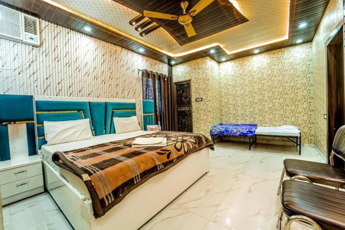 Un dormitorio con cama, mesita de noche, silla, banco y ventilador de techo.