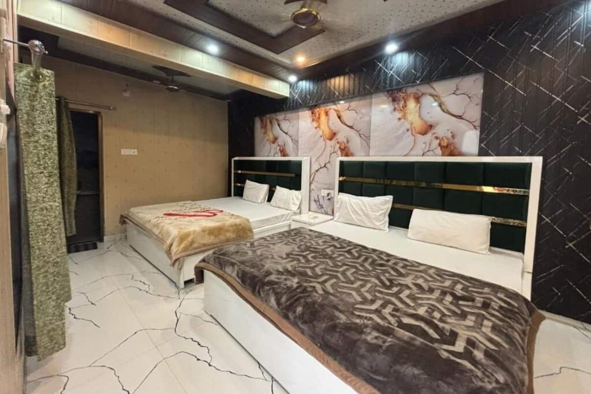 Habitación de hotel con dos camas, un espejo grande y una alfombra estampada.